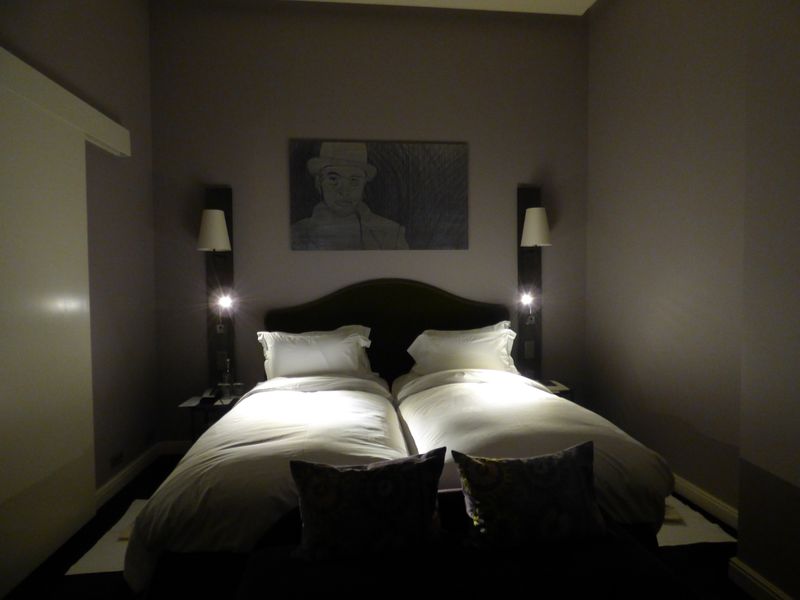 A bedroom with two beds and a painting on the wall