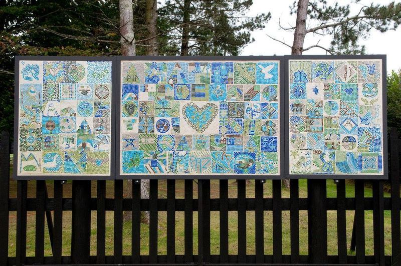 Three paintings on a wooden fence with trees in the background
