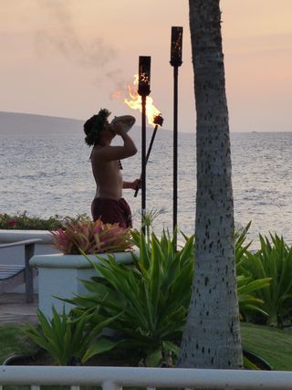 A man blowing a torch in front of the ocean