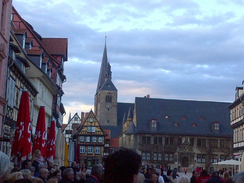 A crowd of people are gathered in front of a church with a clock tower