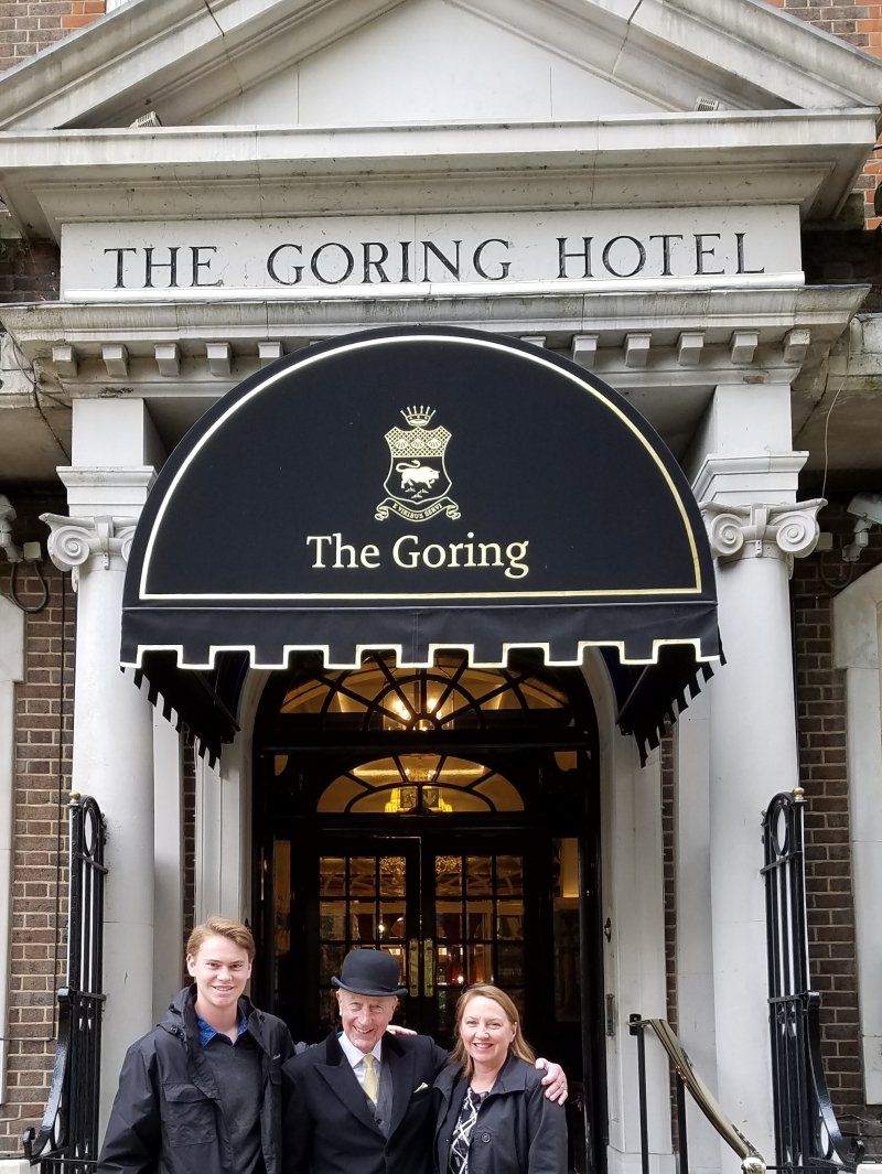 Three people are posing in front of the goring hotel