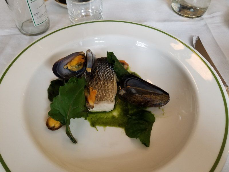 A plate of food on a table with a bottle of water in the background
