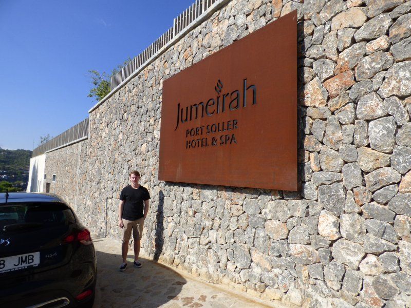 A man is standing in front of a large sign that says jumeirah
