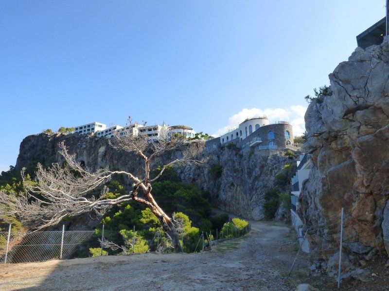 A dirt road going up a hill with a building in the background