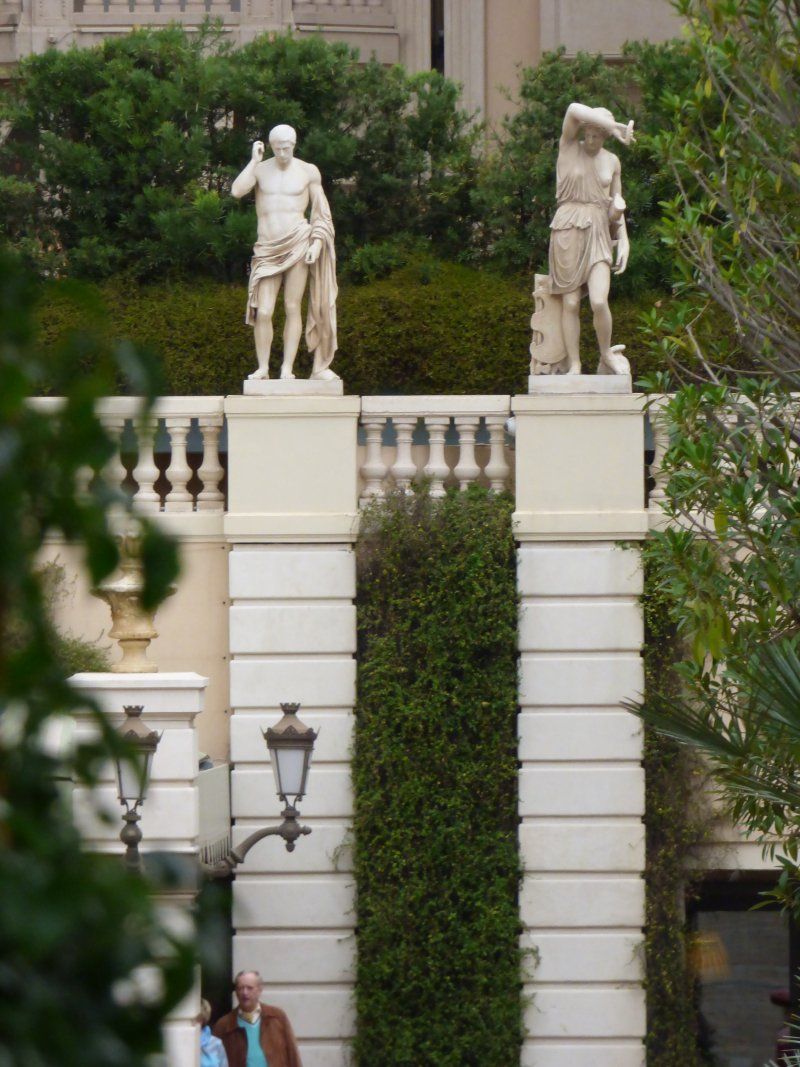 A statue of a man standing on top of a white pillar
