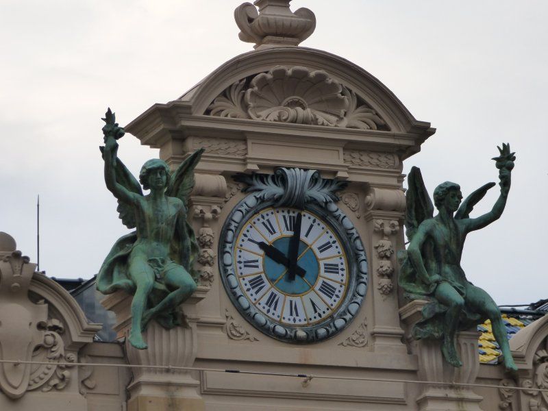 A clock on a building with two statues on it