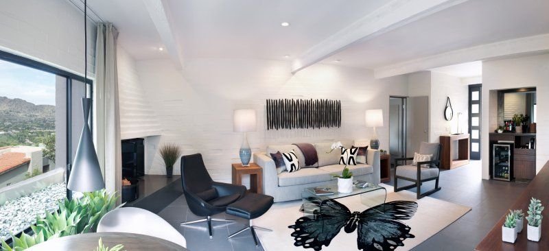 A living room with a white couch and black chairs