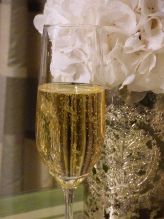 A glass of champagne is sitting on a table next to a vase of flowers.