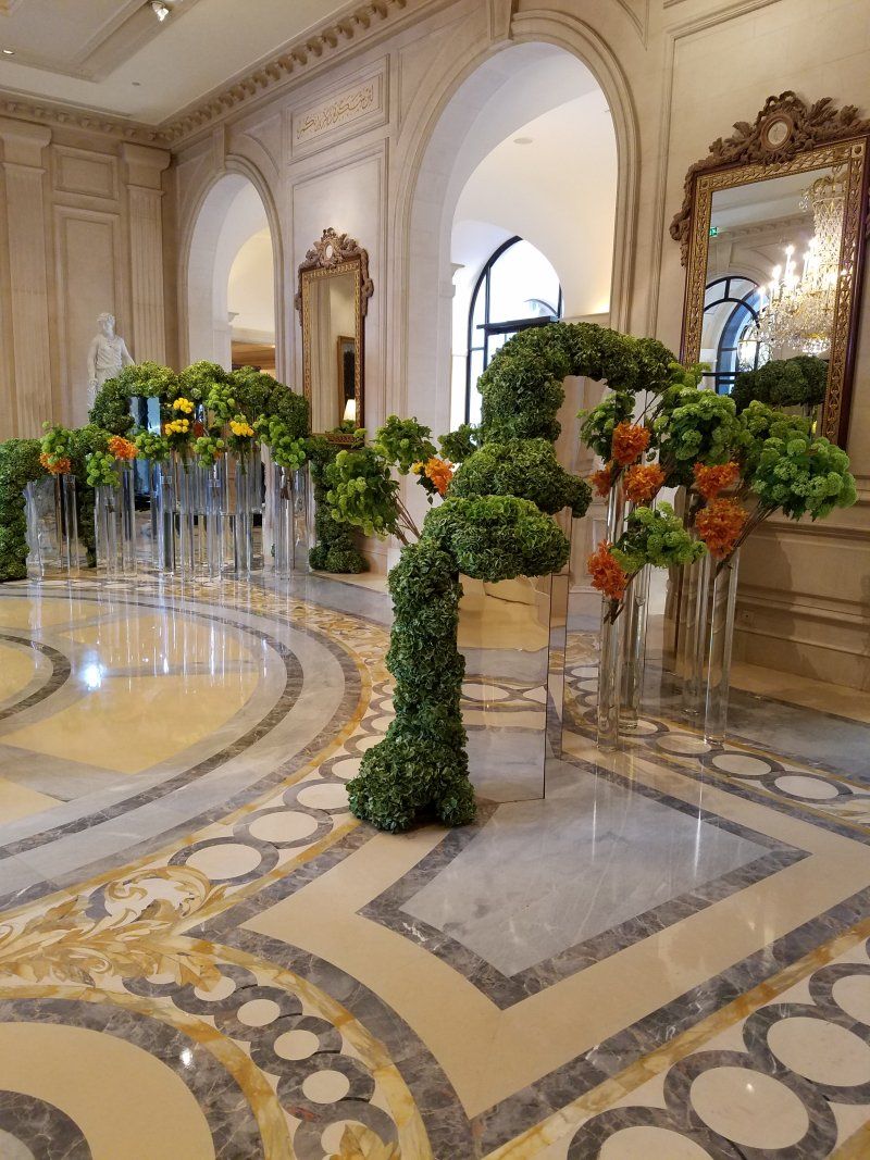 A large room with a marble floor and a lot of flowers in vases.