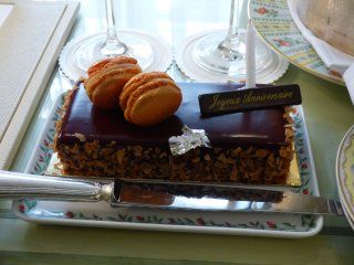 A chocolate cake with macarons and a candle that says joyeux anniversaire