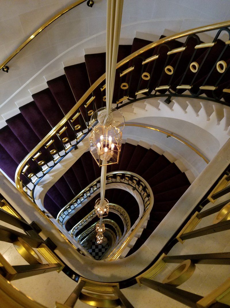 A spiral staircase with purple carpet and gold railing