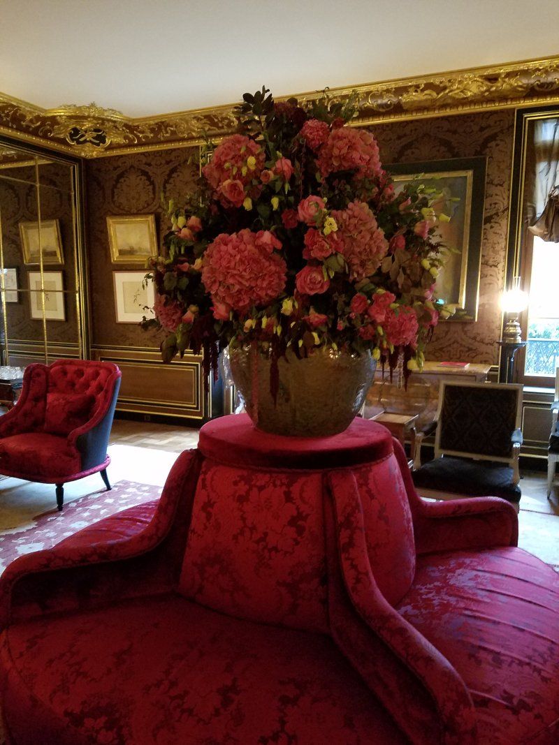 A vase of flowers is sitting on top of a red chair in a living room.