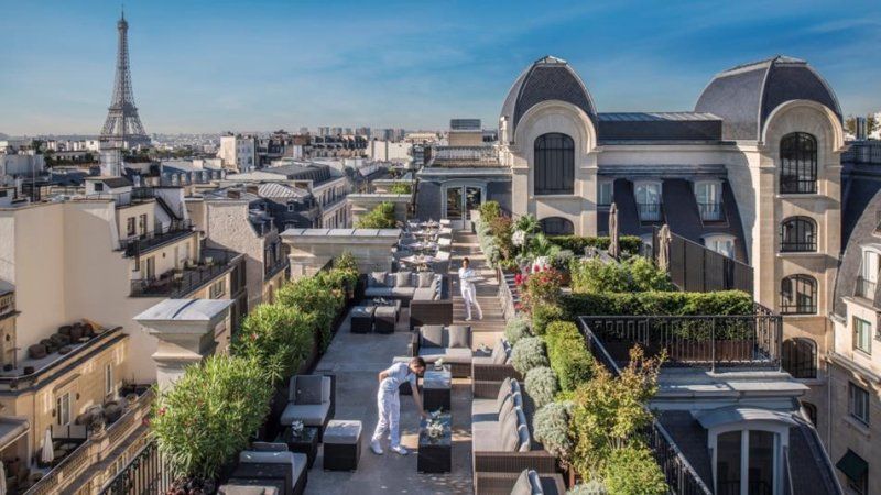 An aerial view of a rooftop terrace in paris with the eiffel tower in the background.