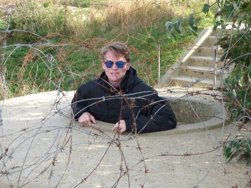 A man wearing sunglasses is sticking his head out of a hole in the ground