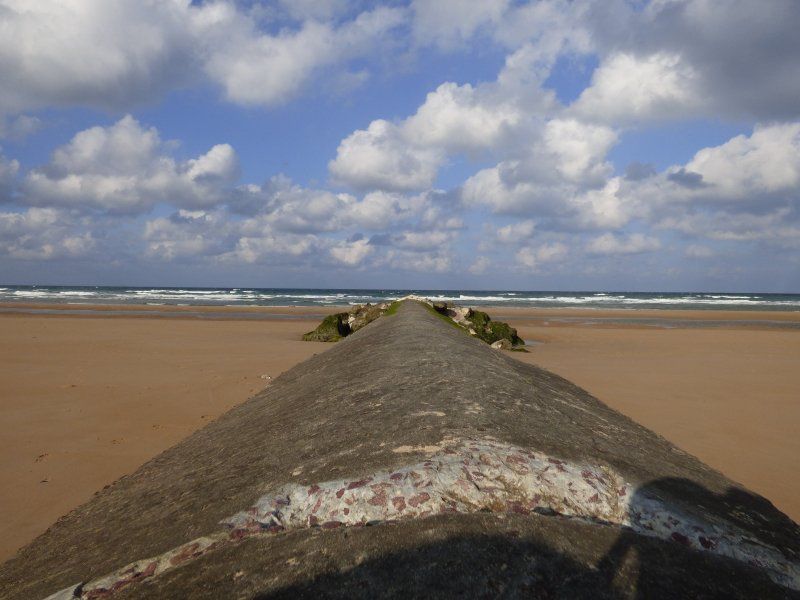 A sandy beach with a concrete block in the foreground