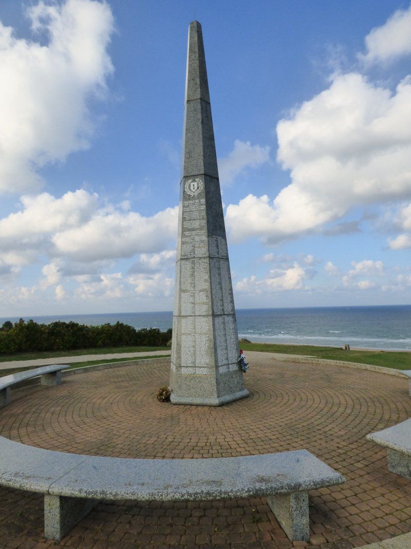 A large stone obelisk with a clock on top of it