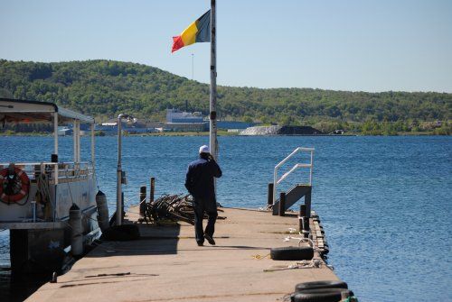 A man is standing on a dock talking on a cell phone.