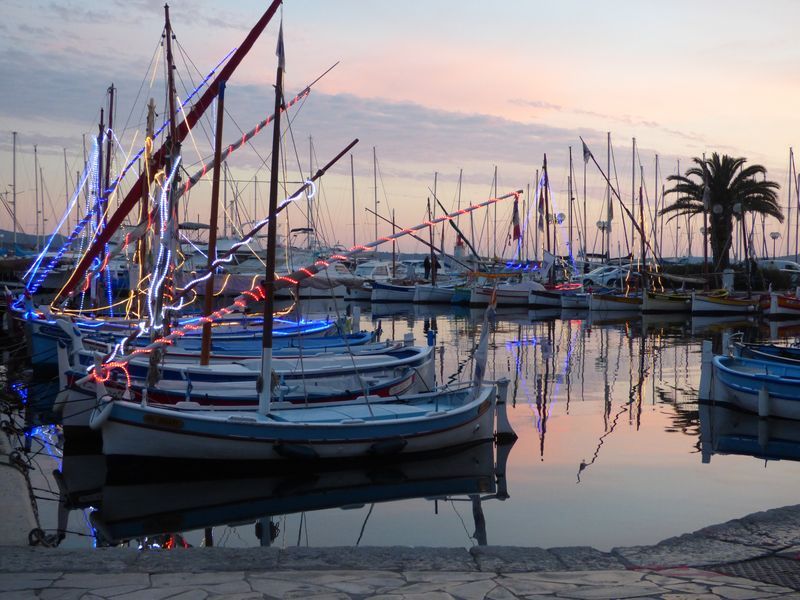 A row of boats are docked in a harbor at sunset.