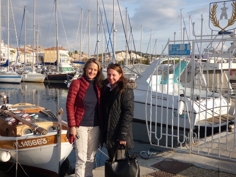 Two women are posing for a picture in front of a boat that says mc8883