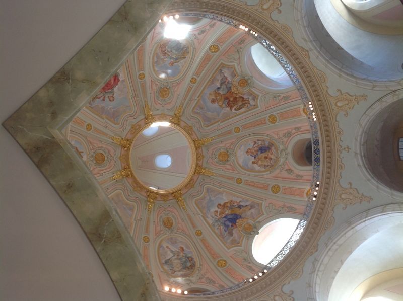 Looking up at the dome of a church with paintings on the ceiling.
