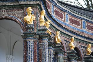A row of statues on top of columns on a building.