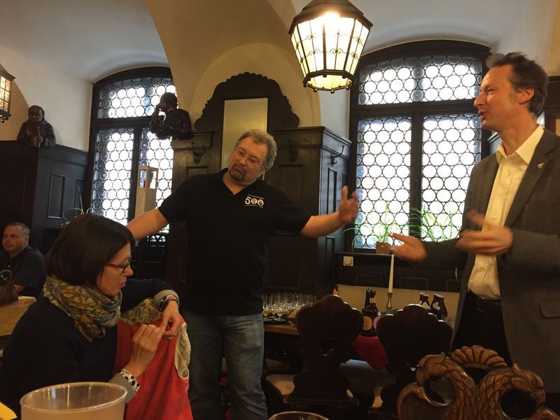 A man in a black shirt is talking to a woman in a restaurant.
