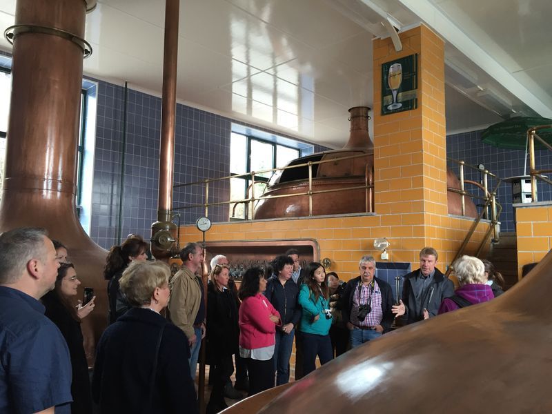 A group of people are standing in a room with copper pipes