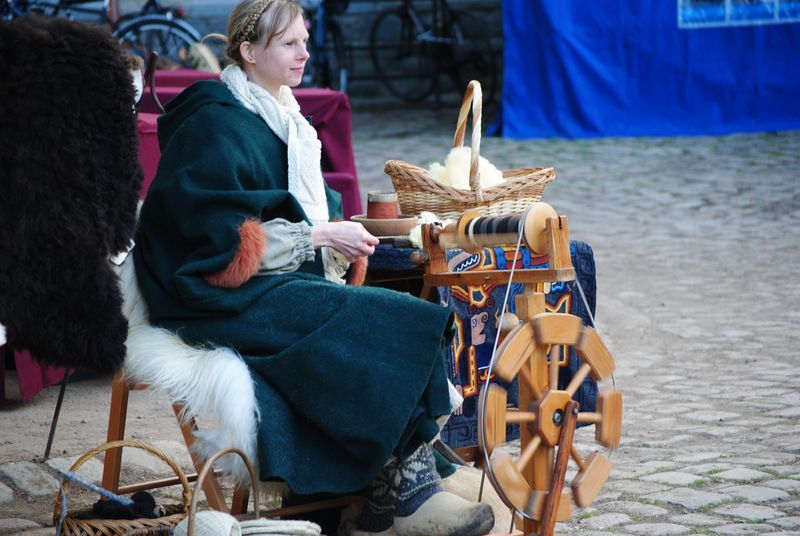 A woman is sitting in front of a spinning wheel