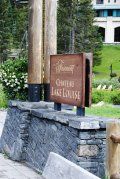 A sign for chateau lake louise is sitting on top of a stone wall.