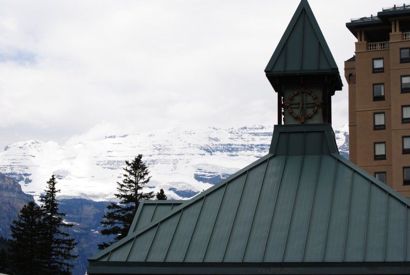 A clock tower on top of a building with mountains in the background
