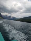 A boat is going down a river with mountains in the background.