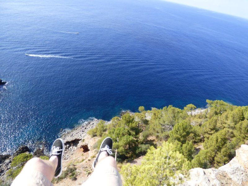 A person 's feet are hanging over a cliff overlooking the ocean