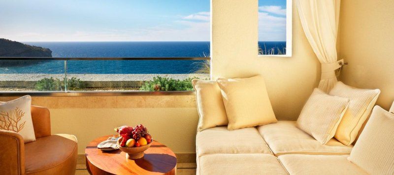 A living room with a couch , chair and table with a view of the ocean.