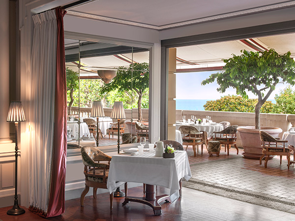 A restaurant with tables and chairs and a view of the ocean