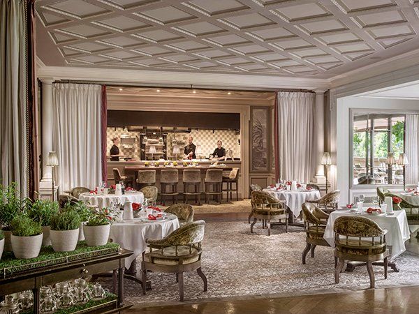 A large dining room with tables and chairs and a kitchen in the background.