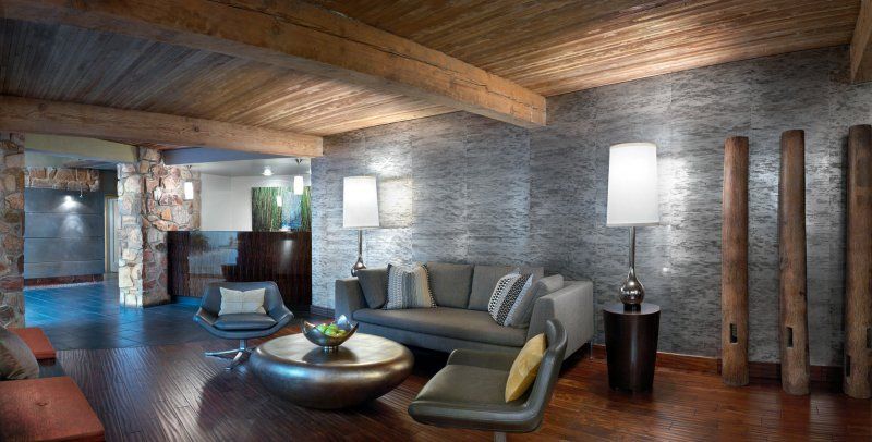 A living room with a couch , chairs , table and lamps.