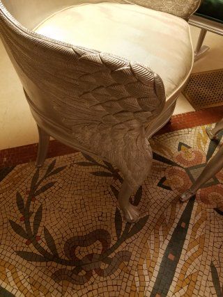 A chair with wings is sitting on a mosaic floor.