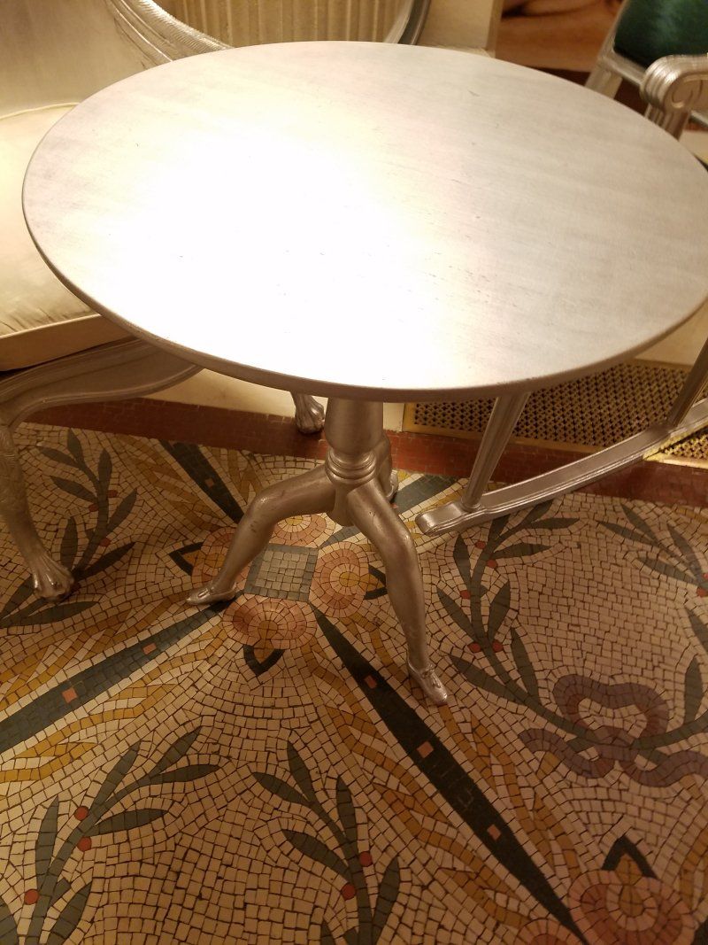 A round table is sitting on top of a mosaic floor.