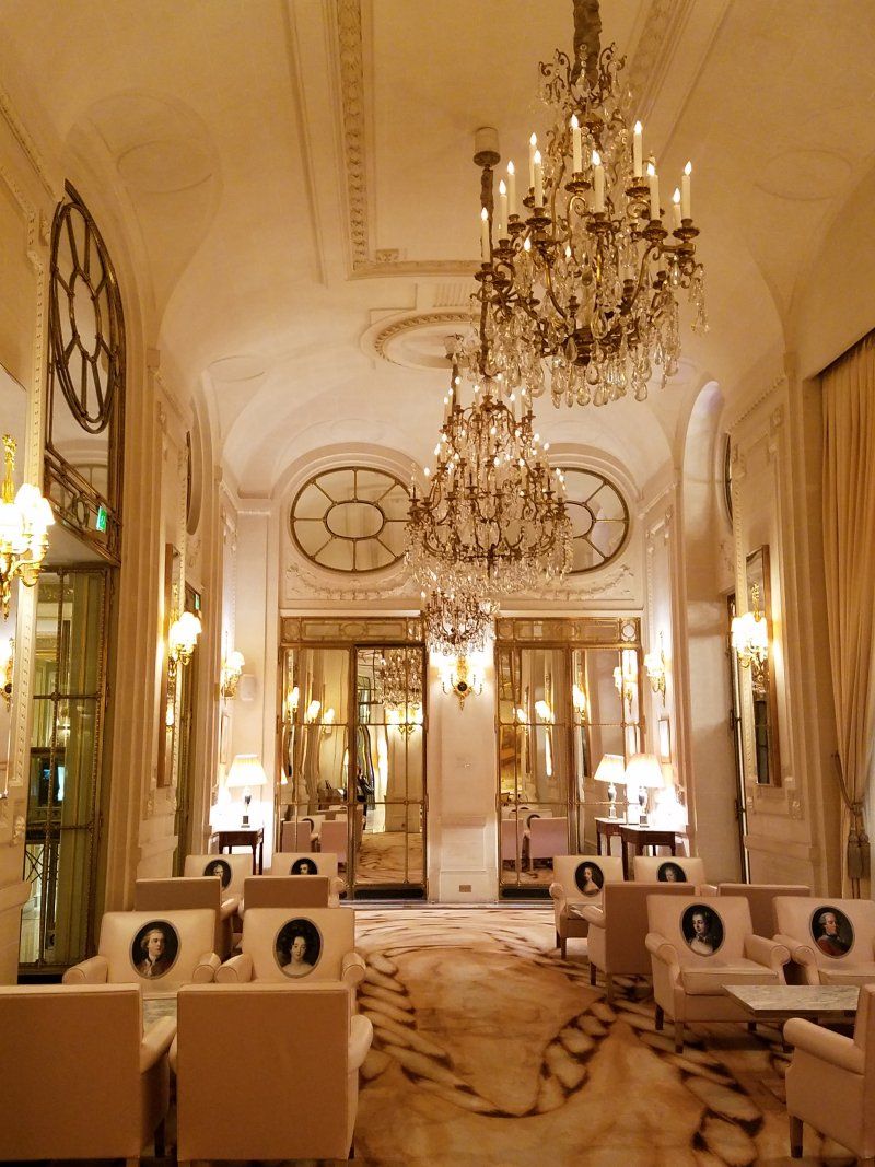 A long hallway with lots of chairs and chandeliers