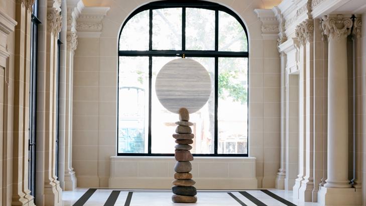 There is a sculpture in the middle of a hallway next to a window.