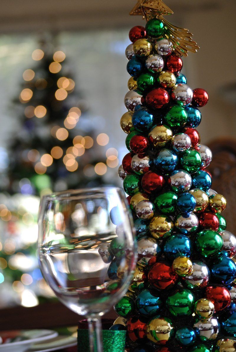 A christmas tree made of bells sits next to a wine glass