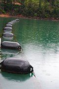 A row of buoys are floating on top of a lake.