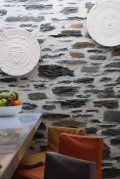 A stone wall with plates on it and a table and chairs in front of it.