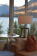 A living room with a couch , table , lamp and a view of a lake.