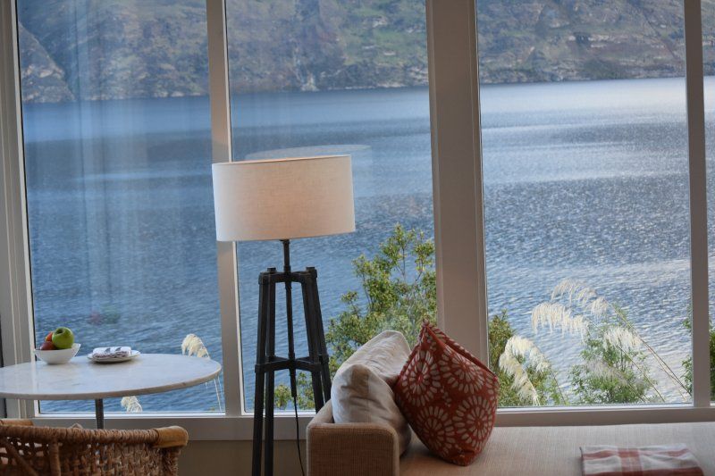 A living room with a couch , table , lamp and a view of a lake.