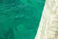 A close up of a swimming pool with turquoise water and a sandy shoreline.