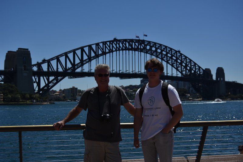 Two men standing in front of a bridge over a body of water