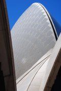 Looking up at the sydney opera house with a blue sky in the background.