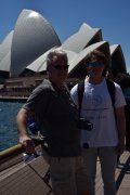 Two men are posing for a picture in front of the opera house in sydney.