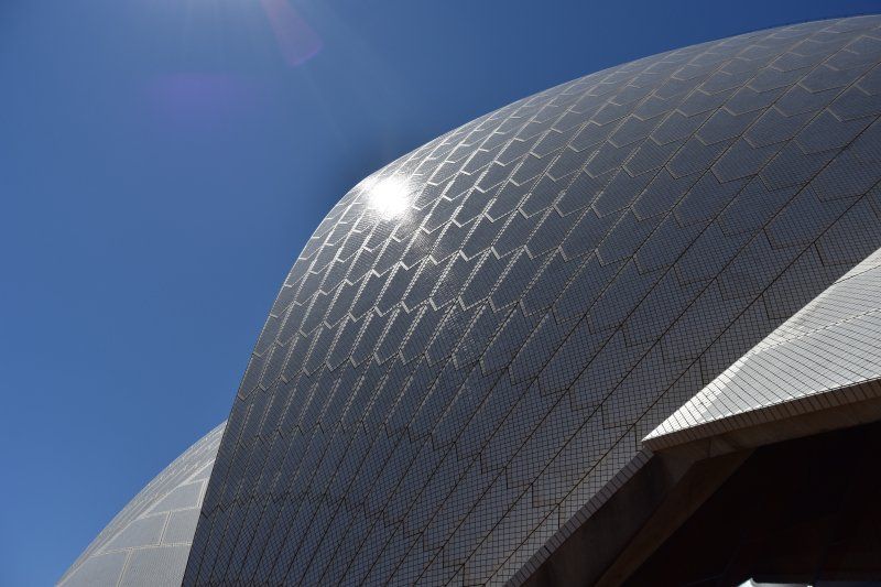 The sun is shining on the roof of the sydney opera house